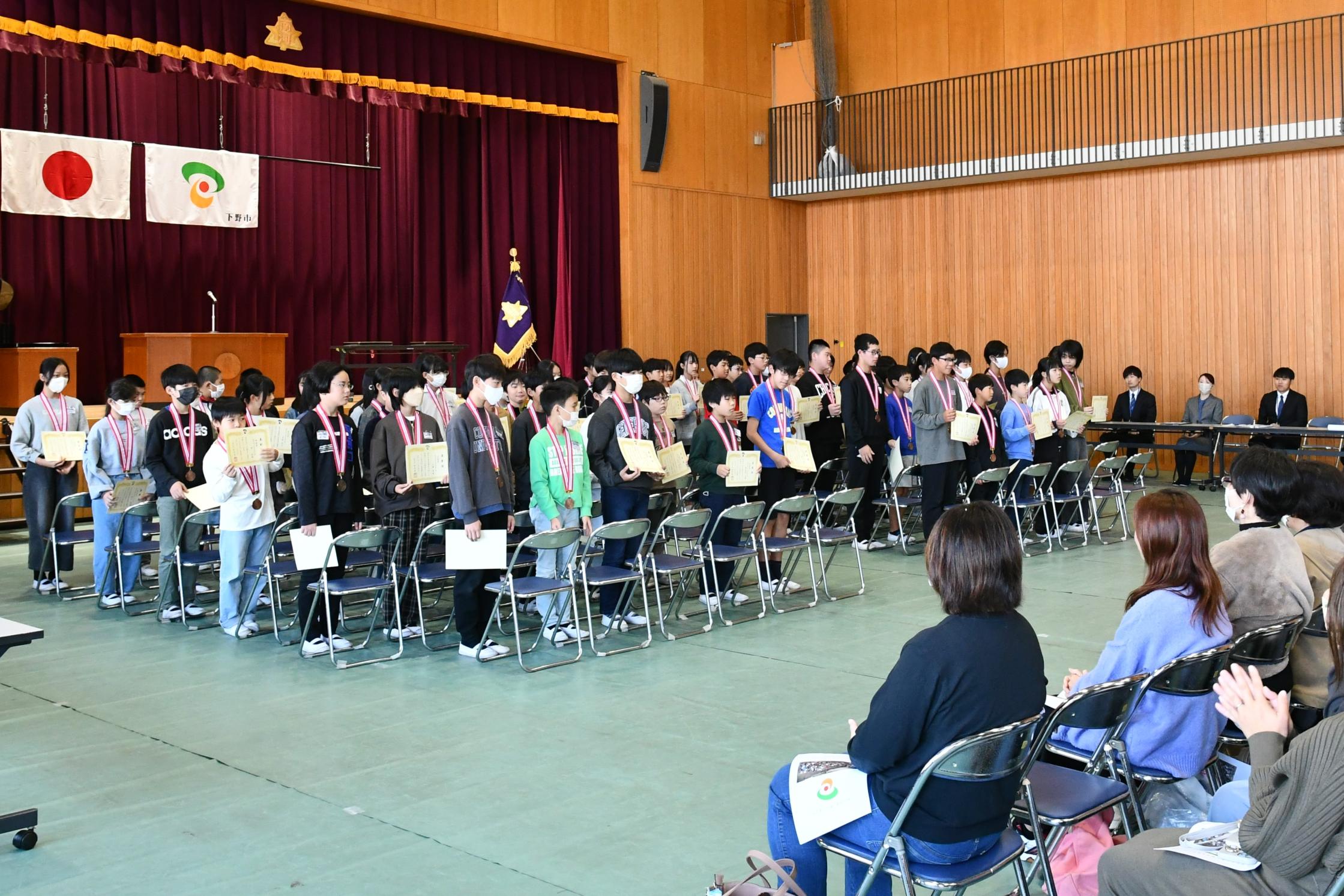 保護者にメダルと賞状を見せる児童